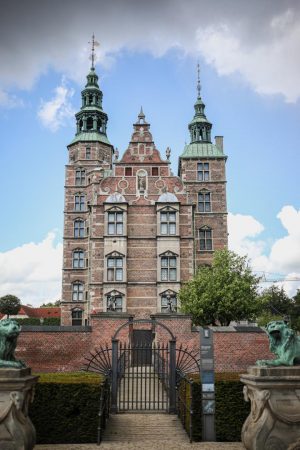 Vue frontale du château de Rosenborg à Copenhague, un imposant bâtiment en briques rouges avec ses deux tours et ses toits en cuivre.