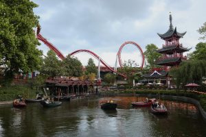 Jardins de Tivoli à Copenhague avec la pagode chinoise et les montagnes russes emblématiques en arrière-plan, ainsi que des bateaux sur le canal. Un des lieux incontournables à visiter dans la capitale danoise.