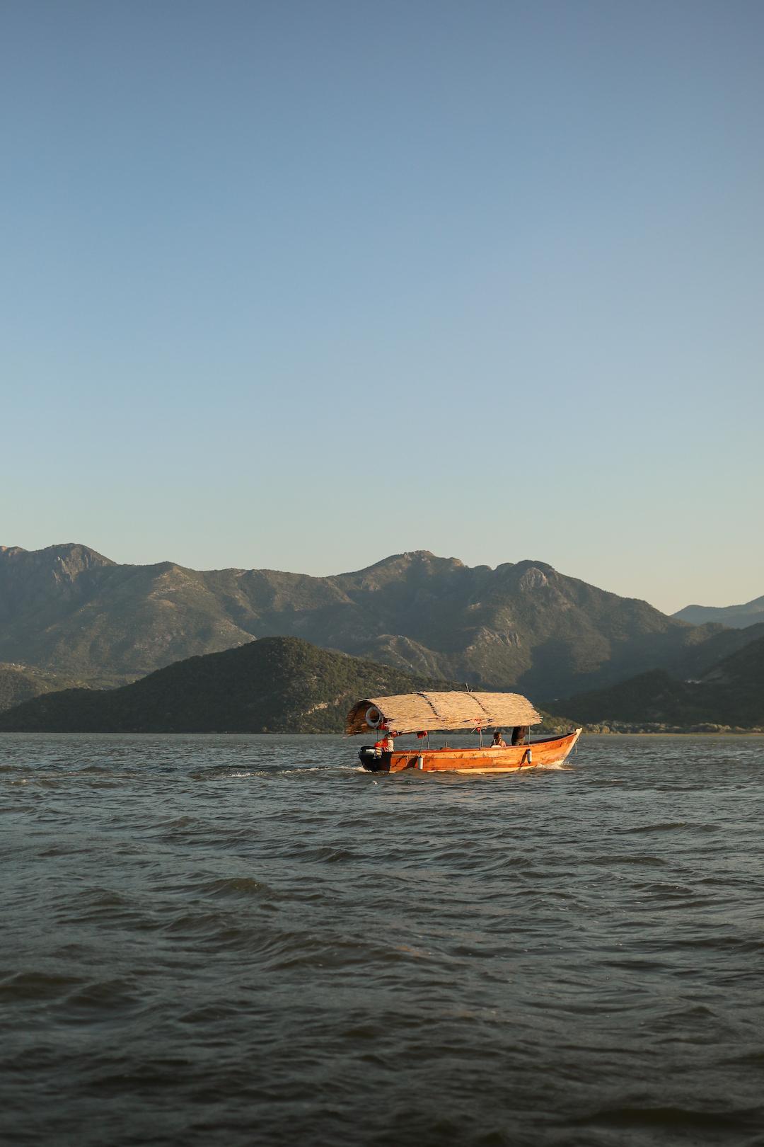 Bateau traditionnel qui vogue sur le lac Skadar au coucher du soleil
